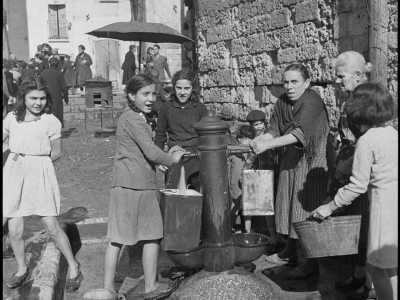 Ma anche donne e ragazzine che riempiono i loro secchi dell�acqua sgorgante da una fontana in ferro (con due rubinetti) in piazza Chiurlia

(F. Alexander Turnbull Library, Welligton, NZ. Ref. DA-03230-F)
